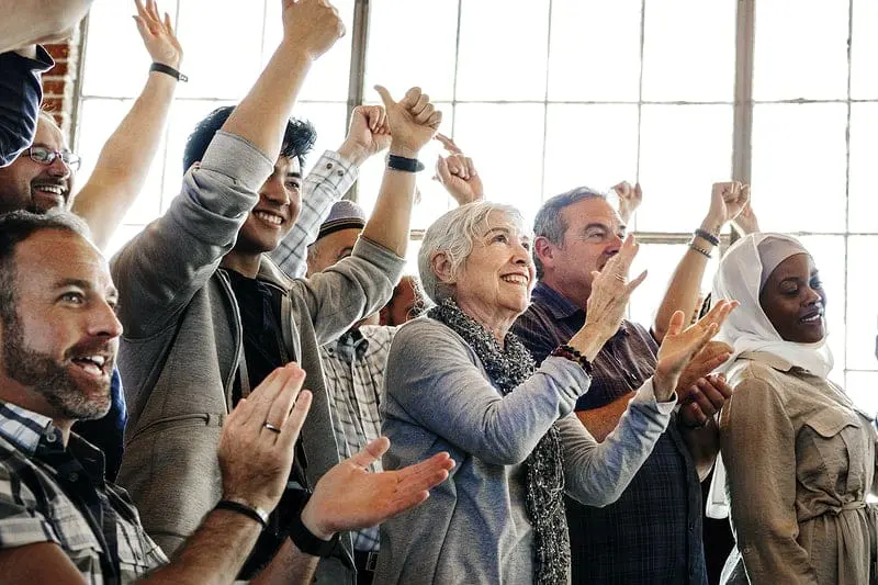 Self-managed HOA 5 Pros and Cons: Discover the Truth 1 Self-managed HOA celebrating fewer conflicts. 8 people from various ages and reaces with their hands up and smiling