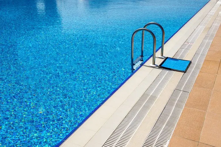 Outdoor hotel swimming pool with blue tiles and ladder