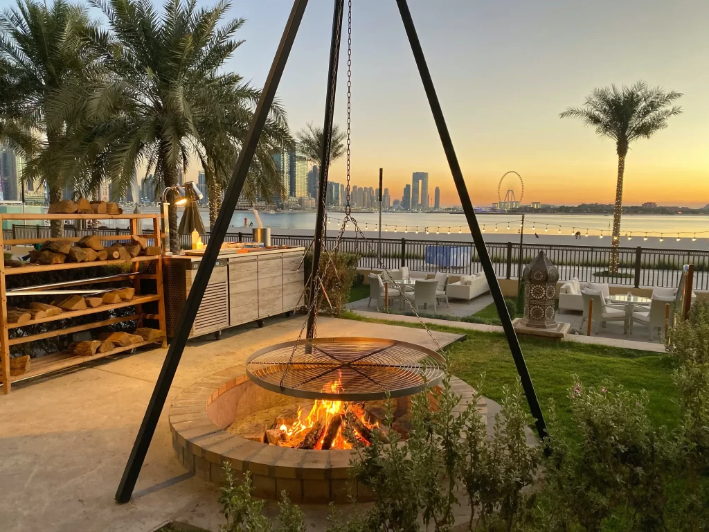 Firepit in beautiful setting with palm trees and sunset over water in the background. HOA outdoor amenities