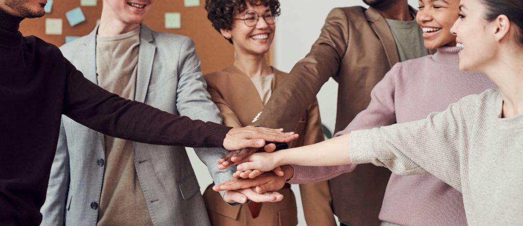 HOA Board Meeting - picture of a group of people smiling and putting their hands together