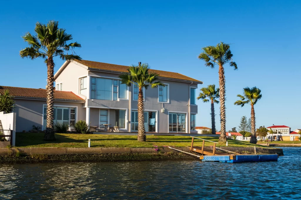 house with palm trees on a canal an example of a short term rentals in HOAs