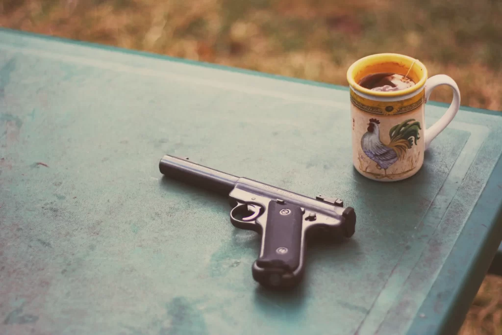 gun on a table with a mug. HOA guns