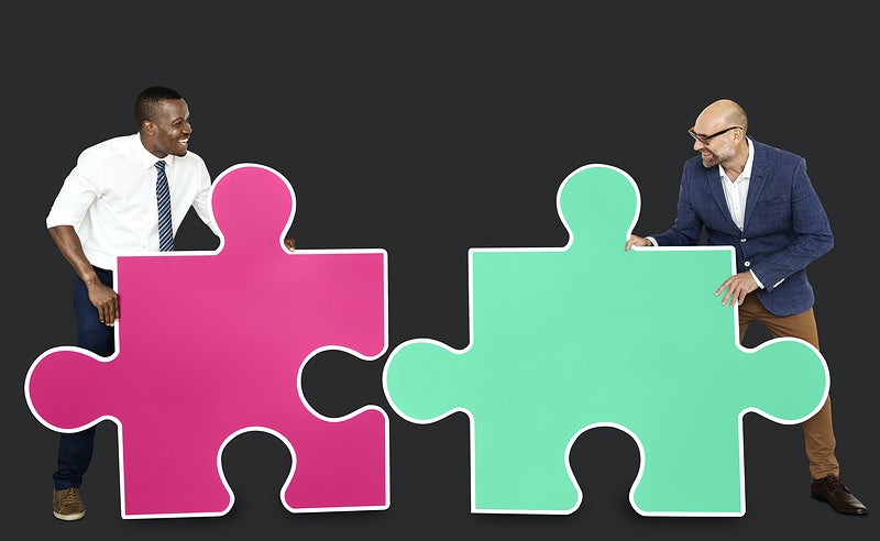 two men fitting puzzle pieces together - community association manager vs property manager