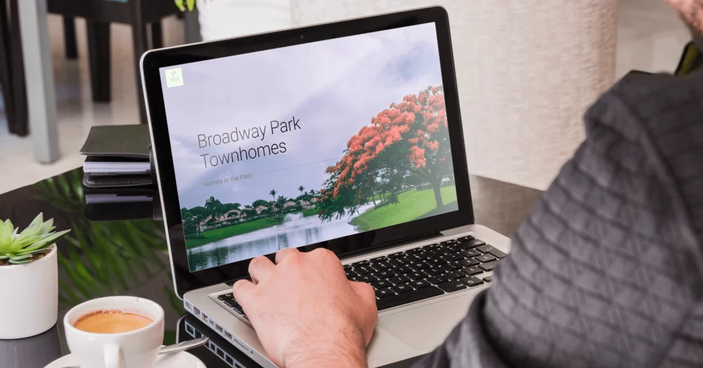 hoa website - image of a woman from behind looking at a laptop with a broadway parks townhomes website
