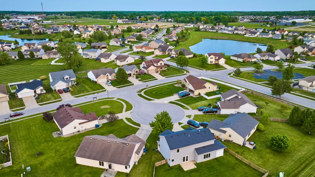 Image of an HOA with green area, swimming pool, cars, and lake. Common and natural areas are one of the benefits of HOAs