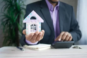 Man in formal clothes holding a house wondering what is property management