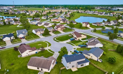 Benefits of HOAs: picture of an HOA with houses, green area, swimming pool, lake and cars.