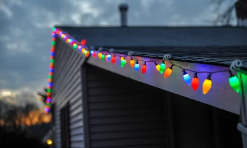 HOA Holidays: A house adorned with vibrant Christmas lights on its roof.