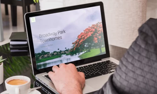 hoa website - image of a woman from behind looking at a laptop with a broadway parks townhomes website