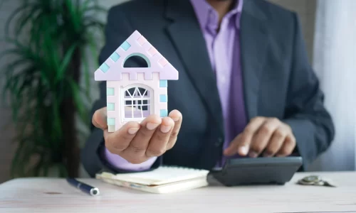 Man in formal clothes holding a house wondering what is property management