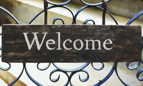 Image of a grid made of metal bars with a sign that reads 'Welcome.' This image represents the HOA Welcome Packet, symbolizing a warm and inviting reception