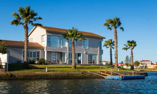 house with palm trees on a canal an example of a short term rentals in HOAs